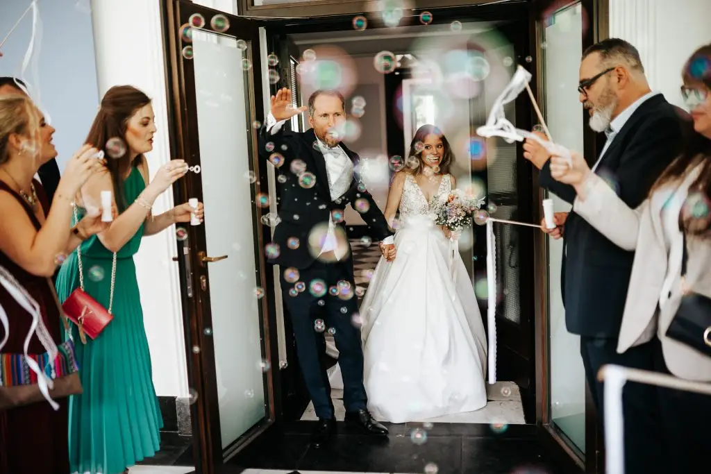 Brautpaar wird während einer Hochzeitsfeier auf Schloss EUlenbroich mit Seifenblasen von den Gästen empfangen.