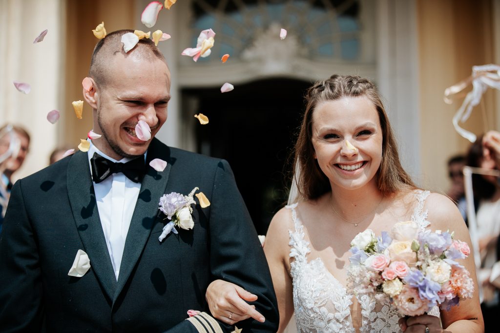 Hochzeitsfoto eines Brautpaares welches auf BUrg Flamersheim geheiratet hat. Dem Bräutigam fliegen Blütenblätter um den Kopf.