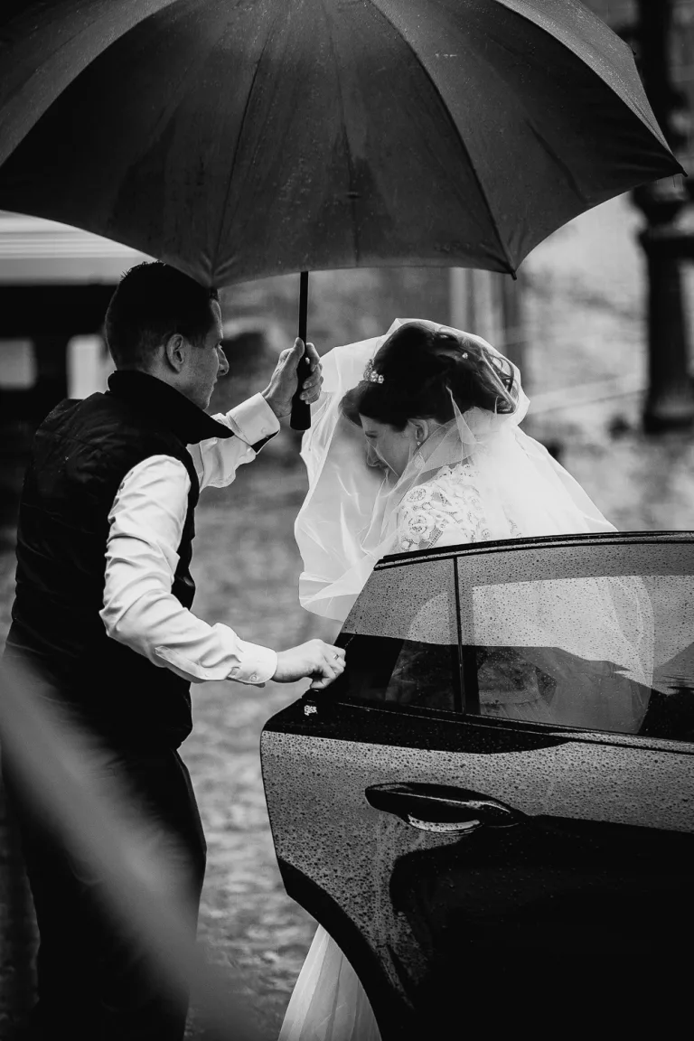 Braut im Regen unter einem Regenschirm.